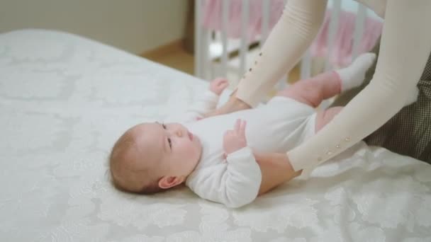 Привлекательная молодая женщина мамочка взять свою маленькую девочку с кровати и взять ее в руки обнимая тщательно и прекрасно — стоковое видео