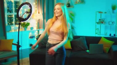 Sosyal medya hesabı için komik videolar çeken gülümseyen büyük karizmatik kadın evde otururken akıllı telefondan video kaydediyor ve hafif bir yüzük kullanıyor.