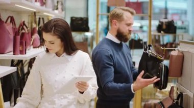 Kamera satıcısına yakın çekim çok çekici dijital tablet kullanarak fiyat değişikliklerini yazarken diğer müşteri de aksesuar dükkanındaki çantalara bakıyor.