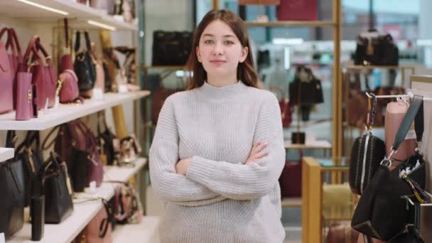 Verbazingwekkend uitziende verkoopster in het midden van accessoires winkel poseren in de voorkant van de camera met kruising handen en glimlachen schattig — Stockvideo