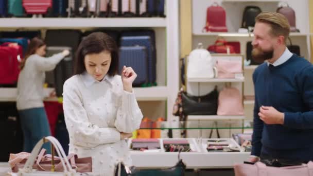 En la tienda de accesorios modernos bastante cliente femenino quiere comprar una bolsa que tiene una conversación con el vendedor que discuten sobre algo — Vídeo de stock