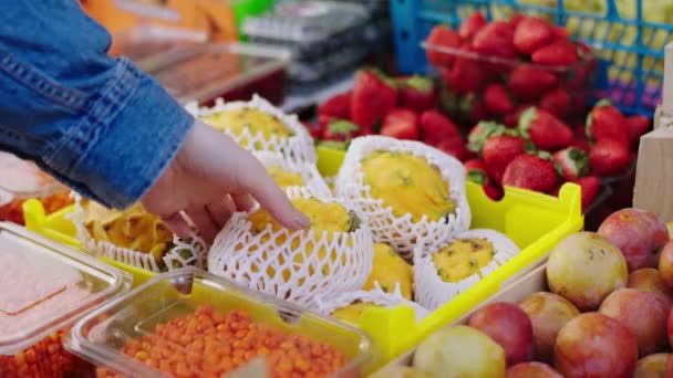 Концепция здорового образа жизни в магазине экологически чистых овощей берет один экзотический фрукт из деревянной коробки — стоковое видео