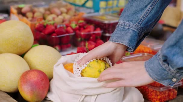 Έννοια της γεωργικής βιομηχανίας και υγιεινό τρόπο ζωής closeup στην κάμερα στο οικολογικό κατάστημα λαχανικών πελάτη προσθέσετε μερικά φρέσκα φρούτα στην οικολογική τσάντα της. 4ια — Αρχείο Βίντεο