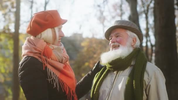 Muito lindo casal velho olhando posando na frente da câmera eles olhando um para o outro no meio do parque em um dia frio de outono — Vídeo de Stock