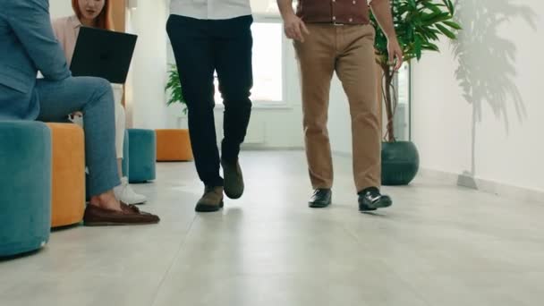 Dois homens de ternos e sapatos de trabalho de estilo clássico estão andando por um corredor de escritório branco. Arri Alexa Mini. — Vídeo de Stock
