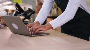 Kahve barındaki yakışıklı Afro-Amerikan barista bir müşteriyle konuşuyor ve arka plandaki meslektaşı yeni siparişi vermeye başlarken bilgisayardan yazdığı siparişi alıyor.