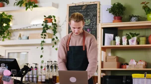 I kaféet snygg barista kille poserar framför kameran och korsar händerna leende stora och ser rakt in i kameran — Stockvideo