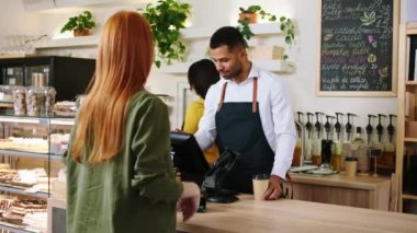 Kahve dükkanındaki rahat atmosfer müşterisi bayan kahvesini dükkandan alıyor. Kahveci adam çok karizmatik gülümsüyor. Terminale kredi kartını taraması için veriyor.