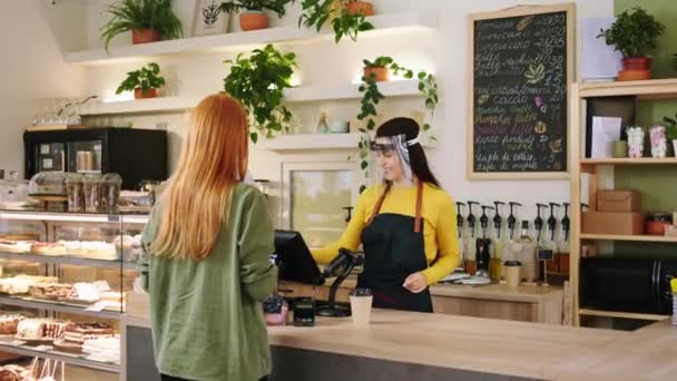Nella caffetteria donna barista ritirare gli ordini dal cliente mentre indossa maschera protettiva nella pandemia di coronavirus — Video Stock