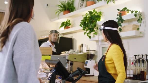 Na frente da câmera no café bar barista mulher tomar a ordem da senhora cliente e dando tarefa para outro barista todas as coisas e cliente vestindo máscaras protetoras conceito de COVID-2019 — Vídeo de Stock