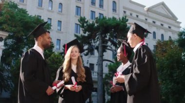 Çok iyi görünümlü çok ırklı mezunlar. Mezun olduktan sonra diplomalarını alıp bu anın tadını çıkarıyorlar.