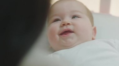 Çocukluk ve annelik kavramı. Mutlu, karizmatik bebek. Kameranın önünde bir yetişkine bakarken kocaman gülümsüyor. 4k