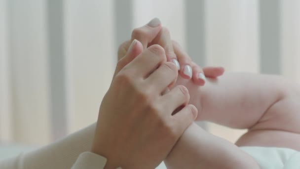 Maternity and childhood concept in front of the camera closeup young mother s hands playing with her baby s legs in the morning — Stock Video