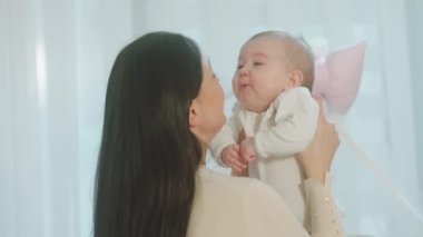 Sevimli kız ve genç annesi birlikte annelerini tartışıyor. O büyük bir gülümseme içinde bebeğiyle iyi vakit geçiriyor.