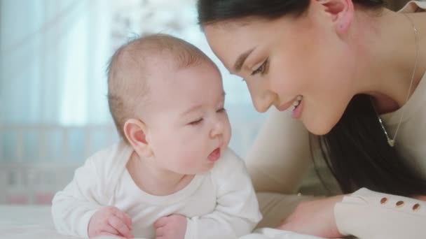 Çocukluk ve sağlık bakımı kavramı anne bebeği yataktan alır ve kameranın önünde bebekle oynamaya başlar. — Stok video