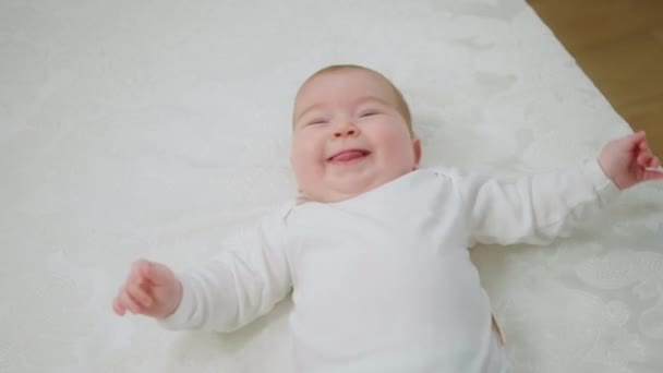 In front of the camera charismatic pretty baby laying down on the bed and giving hands to standing up to her mother concept of childhood and maternity — Stock Video