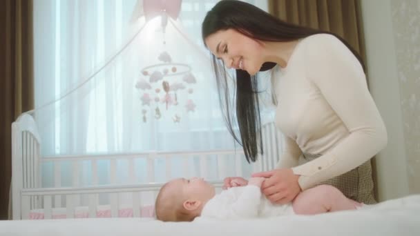 Im Schlafzimmer beschleunigen süße kleine Mädchen zusammen mit ihrer Mutter schöne Zeit miteinander und betrachten sich gegenseitig das Konzept von Mutterschaft und Kindheit. 4k — Stockvideo