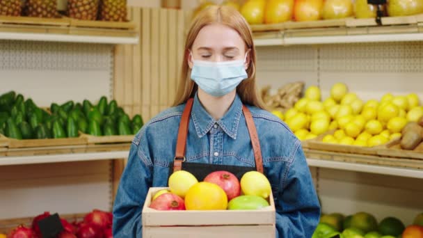 Concept of farming food and fresh harvest in the vegetable shop in front of the camera good looking young woman farmer holding a chest full of organic fresh fruits and looking straight to the camera — Stock Video
