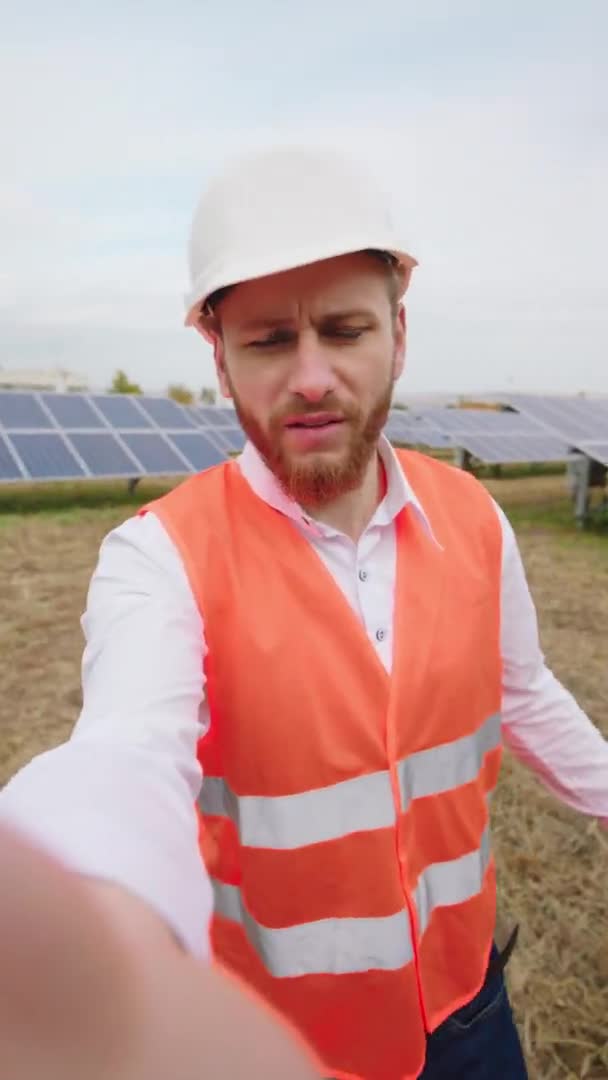 Conceito de energia renovável e inovação ecológica na usina de energia solar um trabalhador ecológico fazendo um vídeo selfie ele falando sobre os painéis solares que ele usa capacete de segurança — Vídeo de Stock