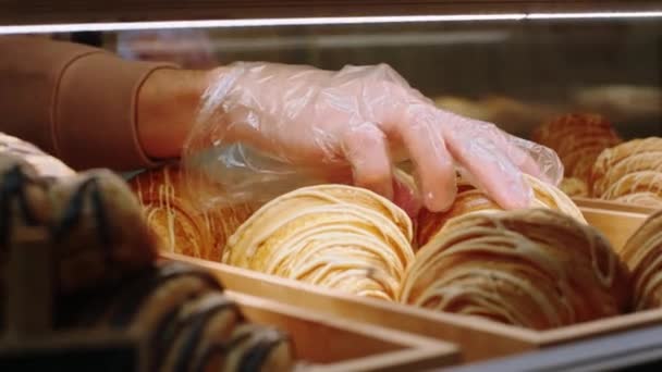 Voor de camera in de koffieshop barista man neemt uit de vitrine koelkast een aantal vers gebakken croissants — Stockvideo