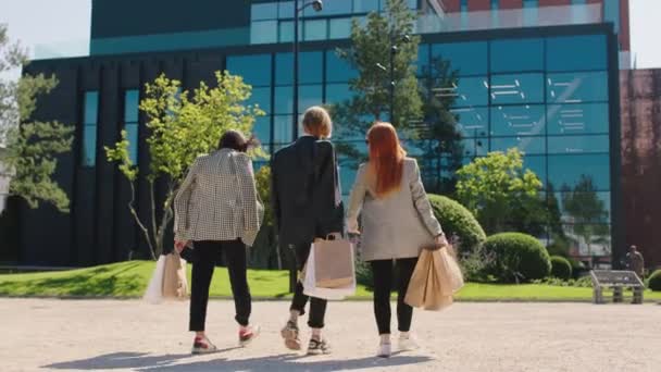 昼食時に買い物袋を持っている3人のビジネス女性が戻ってきて、彼らがオフィスで働いている高いビジネスビルに一緒に歩く。Arri Alexa Mini. — ストック動画