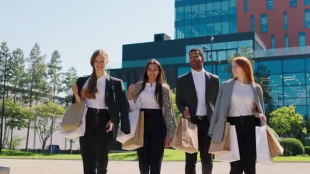 In a modern business centre park group of office workers after their work walking all together holding some eco shopping bags they discussing enthusiastic multiracial concept — Stock Video