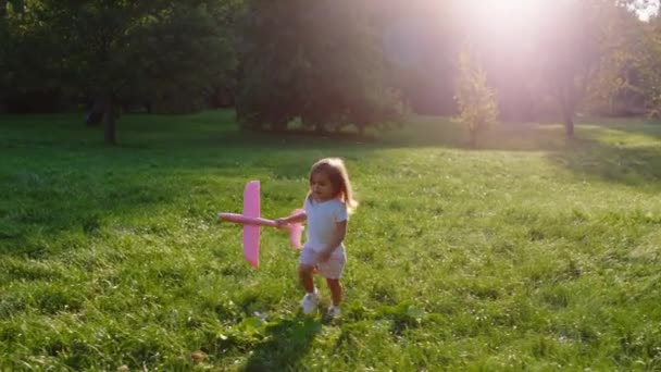 公園の真ん中でかわいい女の子と彼女のスーパーヒーローパパのために幸せな子供時代完璧な晴れた日に飛行機と一緒に遊んで — ストック動画