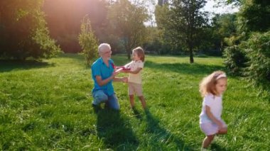 Çimlerin üzerindeki parkta iki karizmatik küçük çocuk ve büyükbaba uçakla birlikte eğleniyorlar. ARRI Alexa Mini 'de çekilen.