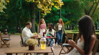 Charismatic couple multiracial black woman and blonde hair guy have a meeting with other friends two beautiful ladies they meet at the cafe