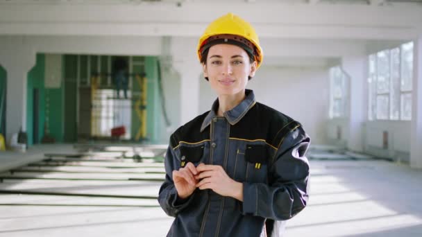 Приваблива молода жінка-архітектор позує перед камерою на будівельному майданчику вона посміхається мило і носить концепцію обладнання безпеки молодих працівників команди — стокове відео