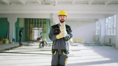 Good looking guy construction worker posing in front of the camera while walking from the construction site he wearing safety helmet and accessories