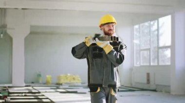 At construction site charismatic construction worker man carrying the building materials in front of the camera