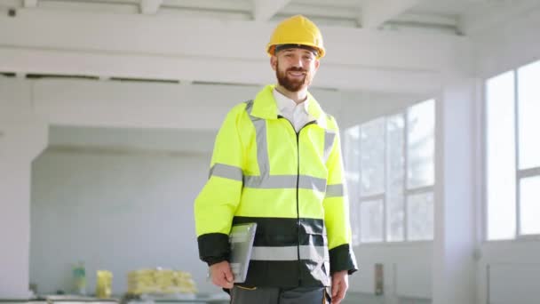 Concept of modern architecture and construction engineer man with the laptop walking through the construction site and analysing the work he wearing safety helmet and equipment — Wideo stockowe