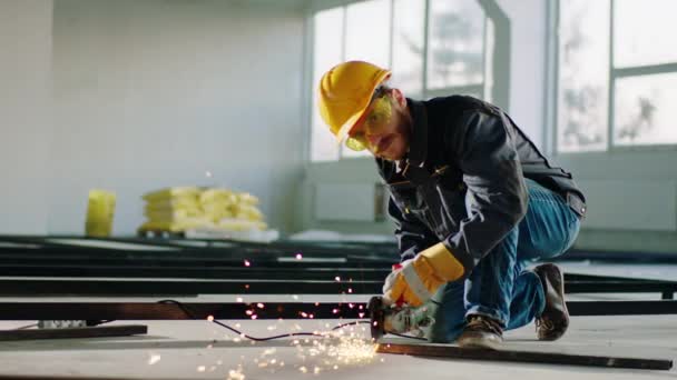 Looking to the camera constructor worker with safety equipment he holding the disc welding machine and cut some metals — Stock videók