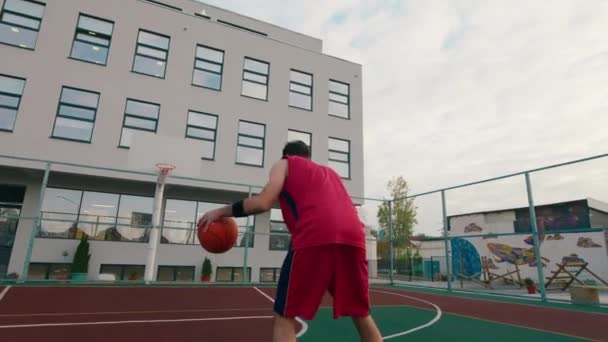 आधुनिक स्टेडियममध्ये बास्केटबॉल खेळणारा एक उंच माणूस तो बास्केटबॉल टोपलीत फेकतो — स्टॉक व्हिडिओ