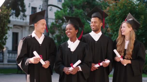 Large smiling multiracial students in their graduation day happy holding the diplomas and posing in front of the camera in the college garden. Shot on ARRI Alexa Mini. — Stockvideo