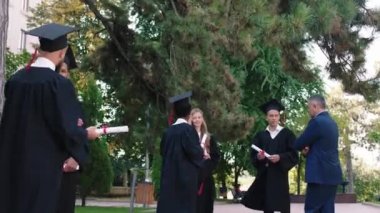 In a perfect sunny day after the graduation group of multiracial students meeting in the college park discussing together and with college principal