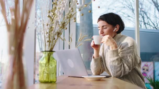 Concept of modern architecture and food industry in the modern coffee shop charismatic woman drinking some hot drink and enjoy the moment looking at the panoramic view from the window while Woking at — ストック動画