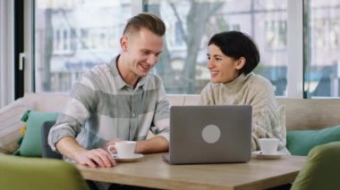 . Very happy young woman and good looking man meeting at the coffee shop they looking at the laptop analysing something and smiling large. 4k