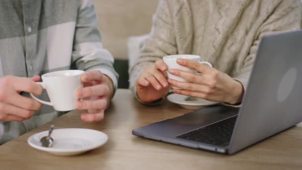 In front of the camera details closeup of a two people in the coffee shop holding the cup of coffee — Stockvideo