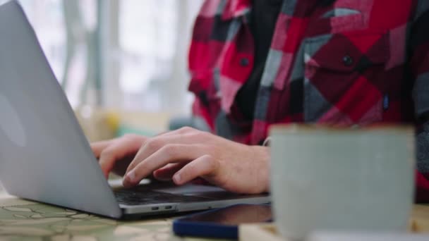 Detalles Captura de cerca con la cámara de un hombre escribiendo y trabajando en su portátil y bebiendo un poco de café al mismo tiempo — Vídeos de Stock