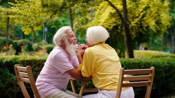 Old man very good looking and beautiful old woman have a beautiful time at cafe they holding hands and discussing about something — Stock video