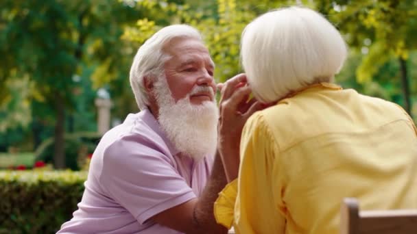 Excited old couple have a romantic time at cafe in the middle of park old man with passion touching her face — Vídeo de Stock