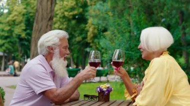 Excited and good looking couple have a romantic time in the middle of the park at the restaurant they drink some wine and enjoy the moment discussing