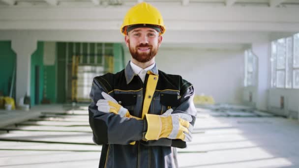 Charismatic construction worker man at construction site wearing special uniform and safety helmet he posing to the camera with a cute smile — Video