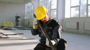 In front of the camera in a large space construction building working in front of the camera construction worker using heavy building materials