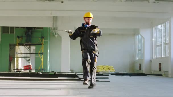 Charismatic and good dancing engineer man at construction site at the end of the day he wearing protective helmet and uniform. 4k — ストック動画