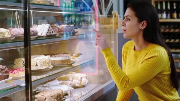 Hermosa mujer cliente en el café de la panadería elegir un desierto de la nevera escaparate que está muy emocionada — Vídeos de Stock