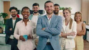 Ofiste bir grup insan ayakta ve kollarını kavuşturuyorlar, kendi kendilerine sevinçle gülümsüyorlar.