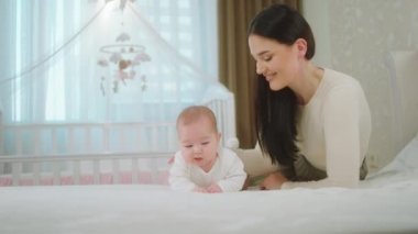 Kameranın önünde gülümseyen bir kadın ve bebeğinin portresi var. Yatağa uzanıp doğrudan kameraya bakıyor. Çok heyecanlı.